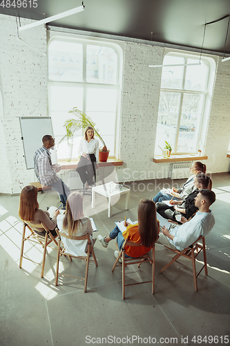 Image of Female caucasian speaker giving presentation in hall at university or business centre workshop