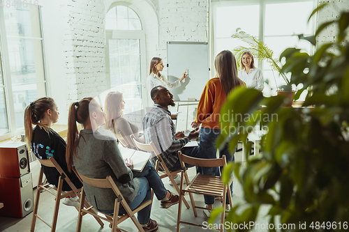 Image of Female caucasian speaker giving presentation in hall at university or business centre workshop