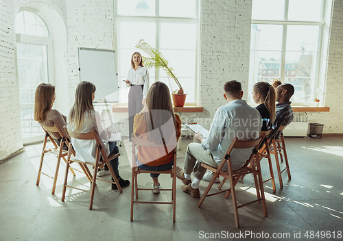 Image of Female caucasian speaker giving presentation in hall at university or business centre workshop