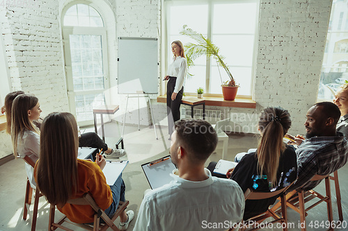 Image of Female caucasian speaker giving presentation in hall at university or business centre workshop