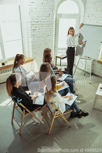 Image of Female caucasian speaker giving presentation in hall at university or business centre workshop