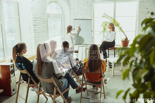 Image of Female caucasian speaker giving presentation in hall at university or business centre workshop