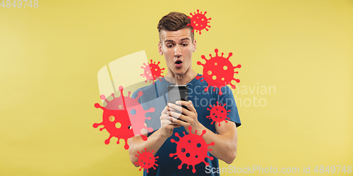 Image of Young man using phone, watching news of coronavirus spreading and worldwide cases, shocked and sad