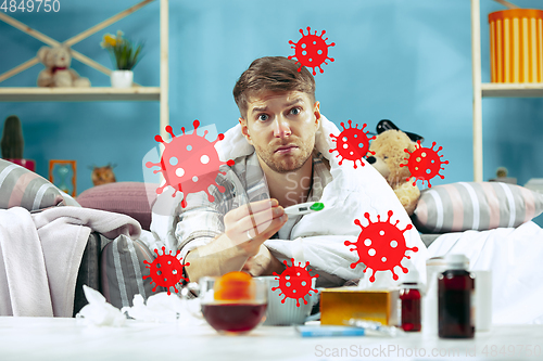 Image of Young man scared of coronavirus spreading and worldwide cases, feeling ill, sick, fever