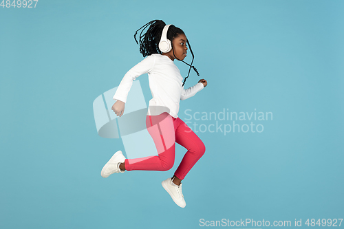 Image of Handsome african little girl portrait isolated on blue studio background with copyspace