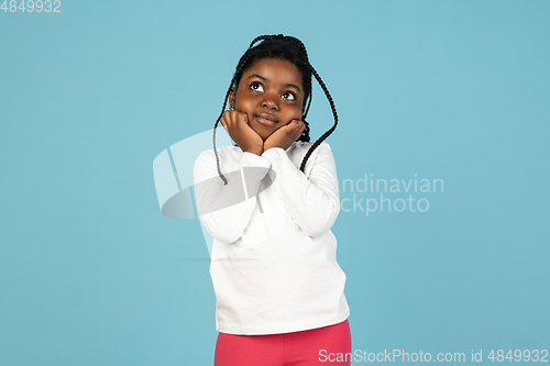 Image of Handsome african little girl portrait isolated on blue studio background with copyspace