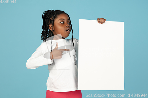 Image of Handsome african little girl portrait isolated on blue studio background with copyspace