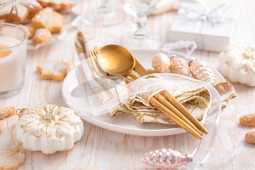 Image of Place setting and Christmas table decorated with ornaments, gingerbread and cookies