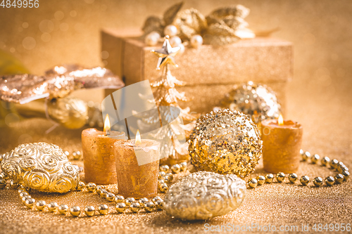 Image of Christmas ornaments, present box and candles in golden tones