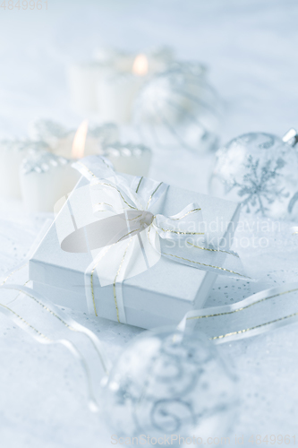 Image of Christmas ornaments, candles and small present in white