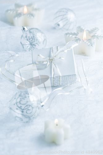 Image of Christmas ornaments, candles and small present in white