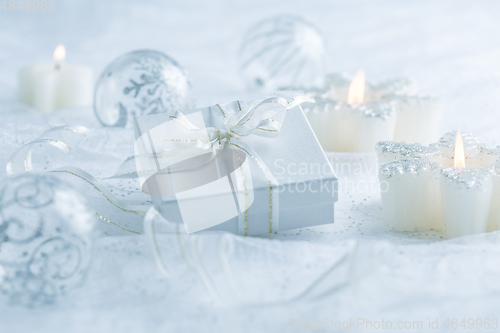 Image of Christmas ornaments, candles and small present in white