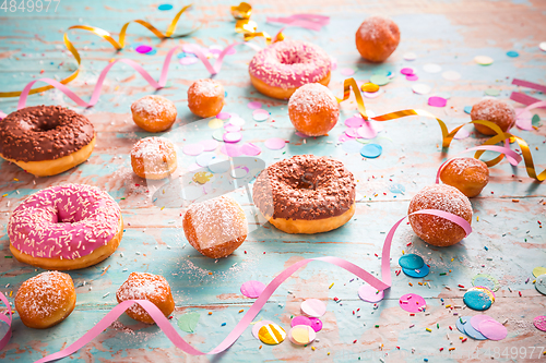 Image of Krapfen, Berliner and donuts with streamers and confetti. Colorful carnival or birthday image