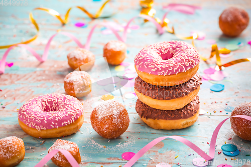 Image of Krapfen, Berliner and donuts with streamers and confetti. Colorful carnival or birthday image