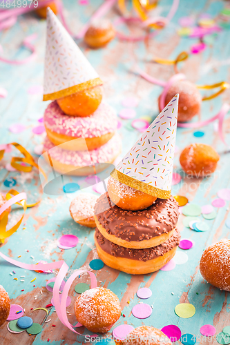 Image of Krapfen, Berliner and donuts with streamers and confetti. Colorful carnival or birthday image