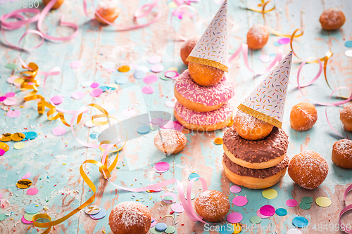 Image of Krapfen, Berliner and donuts with streamers and confetti. Colorful carnival or birthday image