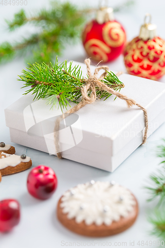 Image of Christmas composition. Christmas gift, fir branches on wooden white background with gingerbread cookie