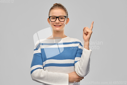 Image of happy teenage girl in glasses pointing finger up