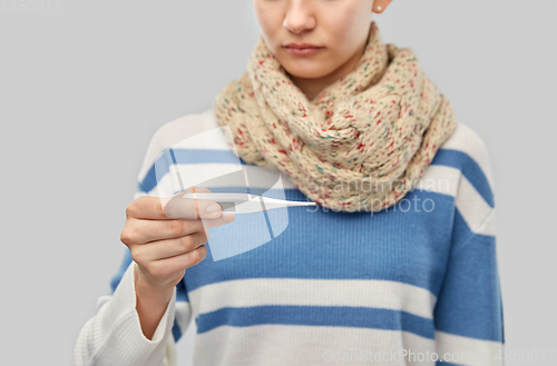Image of sick teenage girl in scarf measuring temperature