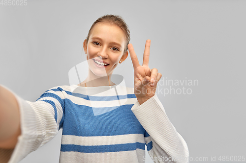 Image of happy teenage girl taking selfie and showing peace