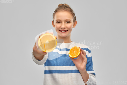 Image of smiling teenage girl in pullover with oranges