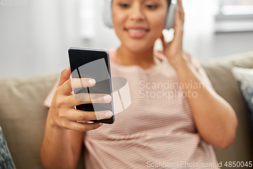 Image of woman with smartphone listening to music at home