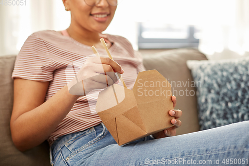 Image of african woman eating food with chopsticks at home