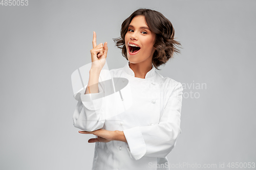 Image of smiling female chef in toque pointing finger up
