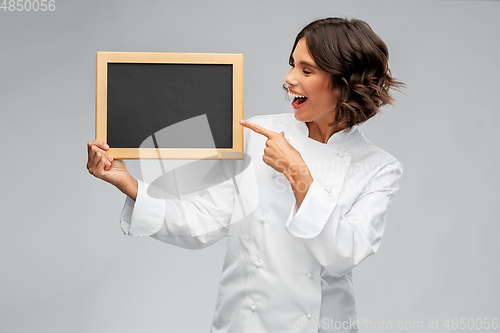 Image of smiling female chef holding black chalkboard