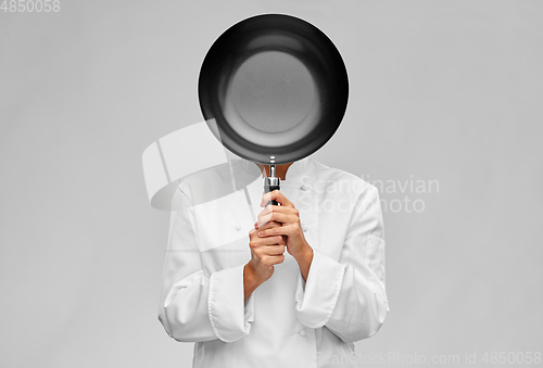 Image of female chef covering her face with frying pan