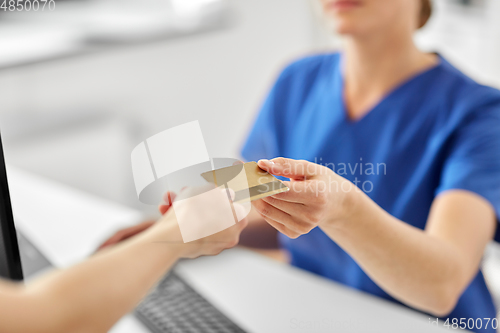 Image of patient giving doctor credit card at hospital