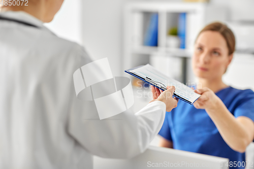 Image of nurse giving clipboard to doctor at hospital