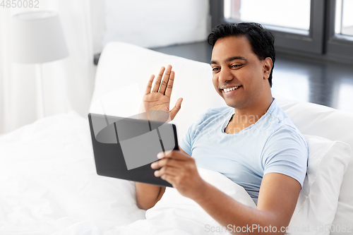 Image of happy man with tablet pc in bed having video call