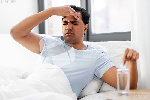 Image of sick man in bed with medicine and glass of water