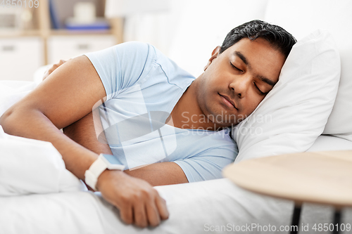 Image of indian man with smart watch sleeping in bed