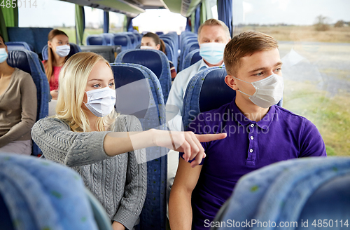 Image of couple of passengers in masks in travel bus