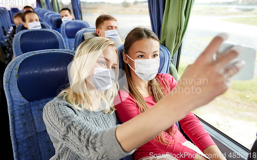 Image of women taking in masks selfie in travel bus