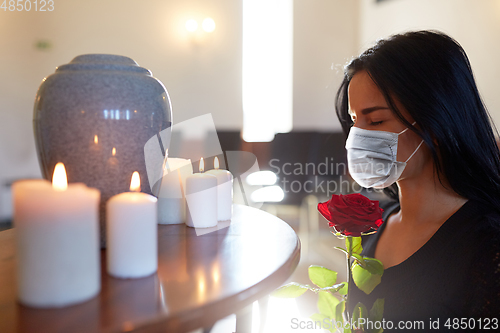 Image of woman in mask with rose at funeral in church