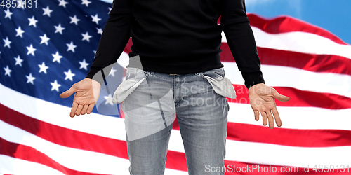 Image of close up of man showing empty pockets over grey