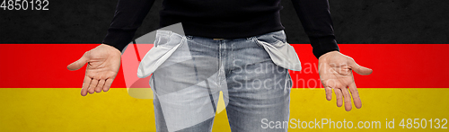 Image of close up of man showing empty pockets over grey