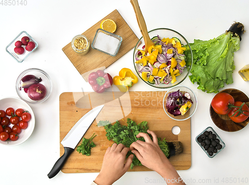 Image of hands preparing parsley for salad on kitchen table