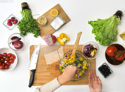 Image of hands cooking vegetable salad on kitchen table