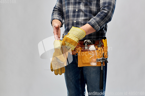 Image of builder with working tools putting gloves on