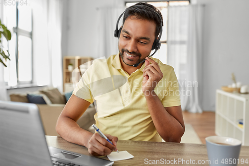 Image of indian man with headset and laptop working at home