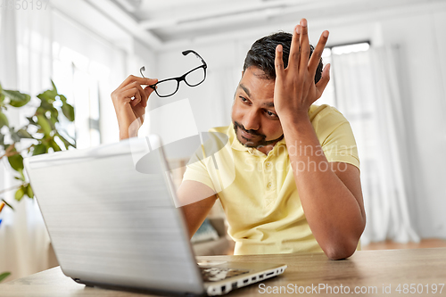 Image of stressed man with laptop working at home office