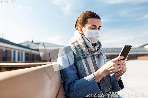 Image of woman in face mask with smartphone in city