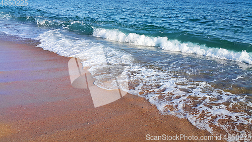 Image of Sea wave with white foam on the coastal sand