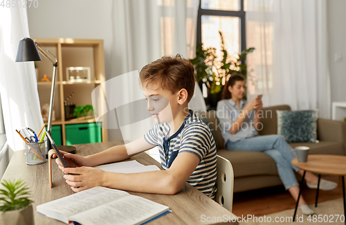 Image of student boy with tablet computer learning at home