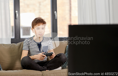 Image of boy with gamepad playing video game at home