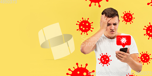 Image of Young man using phone, watching news of coronavirus spreading and worldwide cases, shocked and sad